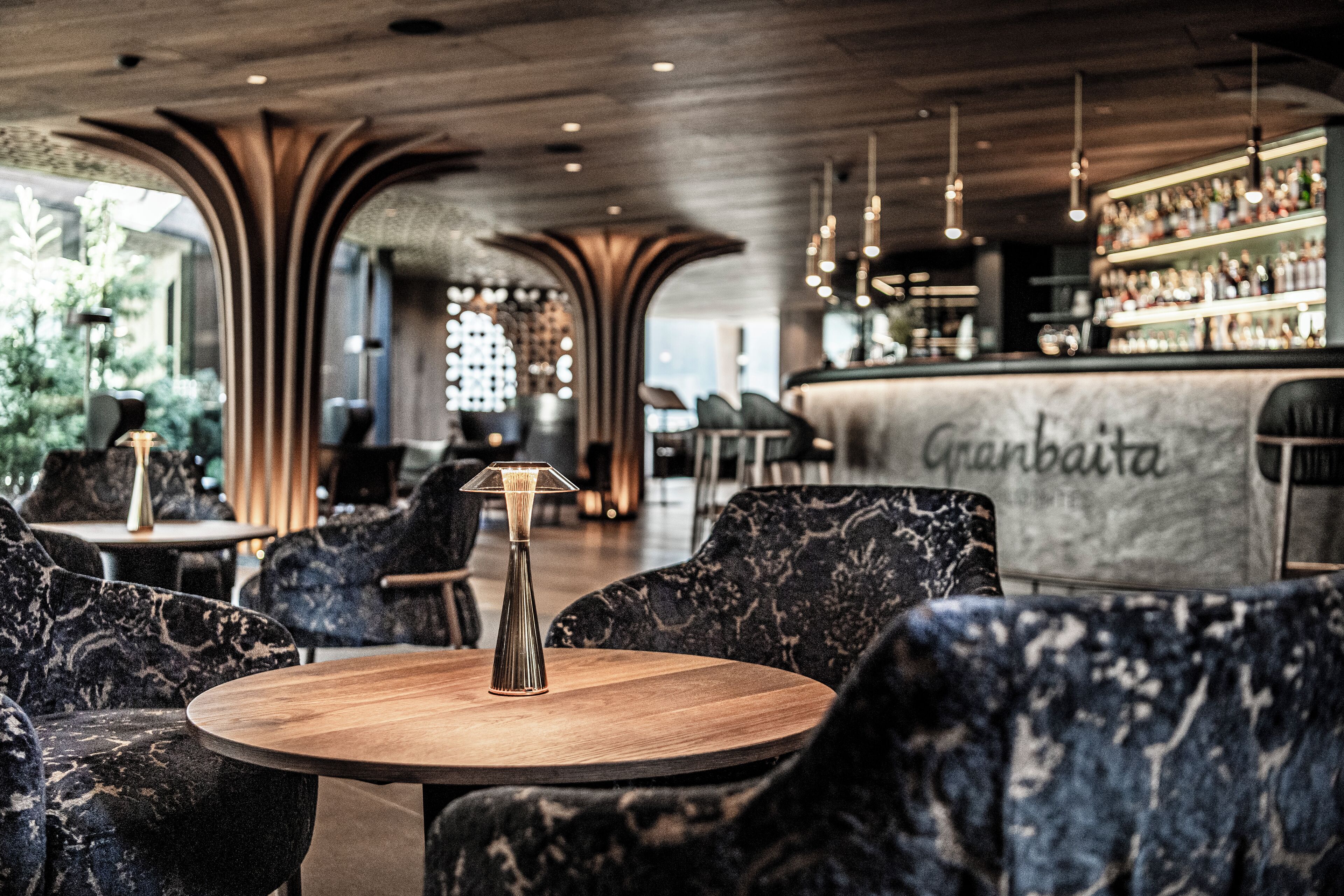 Eine moderne Bar mit einer Marmorplatte und Sitzgelegenheiten mit dunkel gemusterten Polstern.