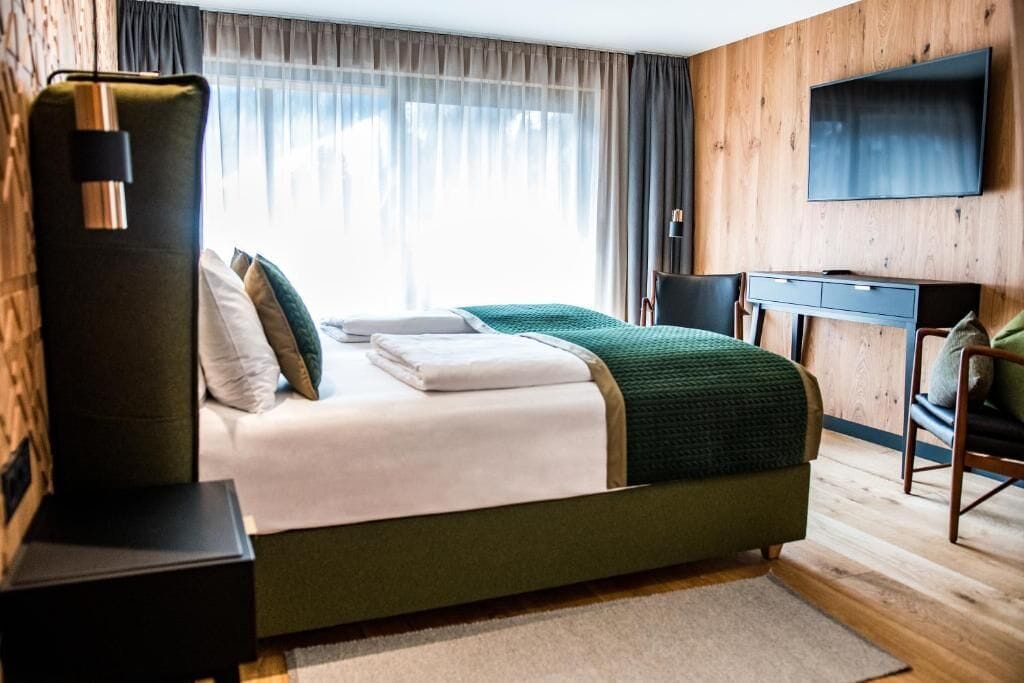A modern hotel room with a large bed, a desk, and a TV.
