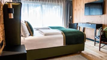 A modern hotel room with a large bed, a desk, and a TV.