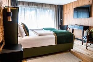 A modern hotel room with a large bed, a desk, and a TV.