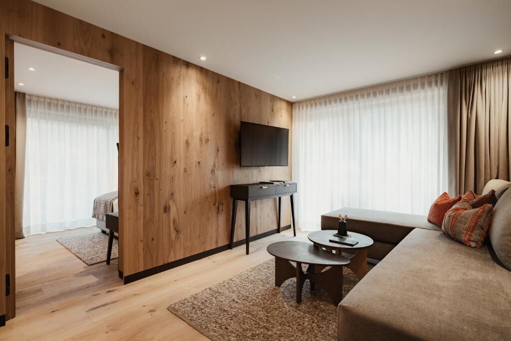 Una sala de estar moderna con una pared de acento de madera, un televisor de pantalla plana, un sofá y una pequeña mesa de centro.