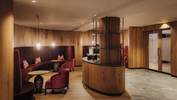A modern lobby with wooden paneling, a curved reception desk, and plush seating areas.