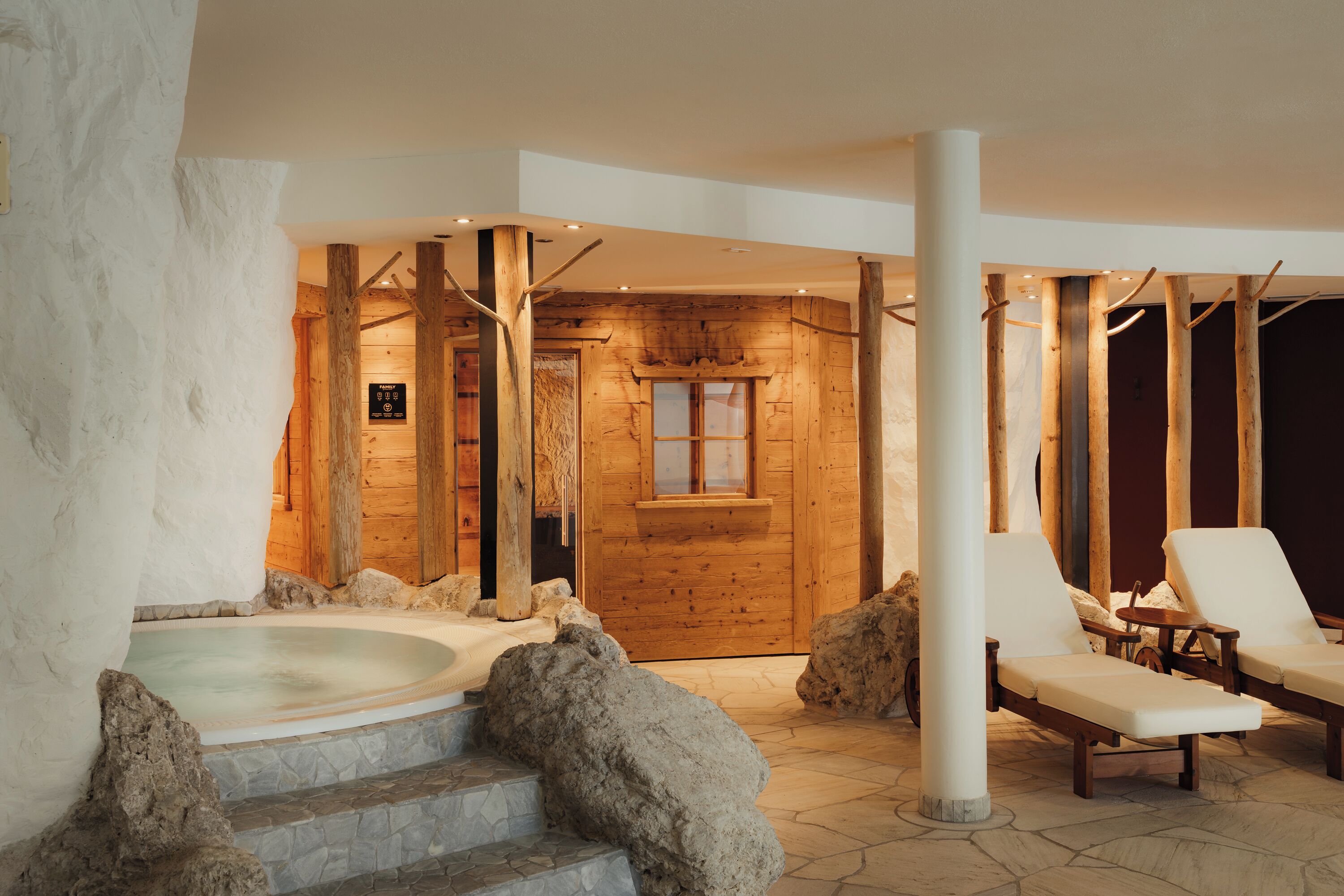 A spa area with a hot tub, wooden walls, and two lounge chairs.