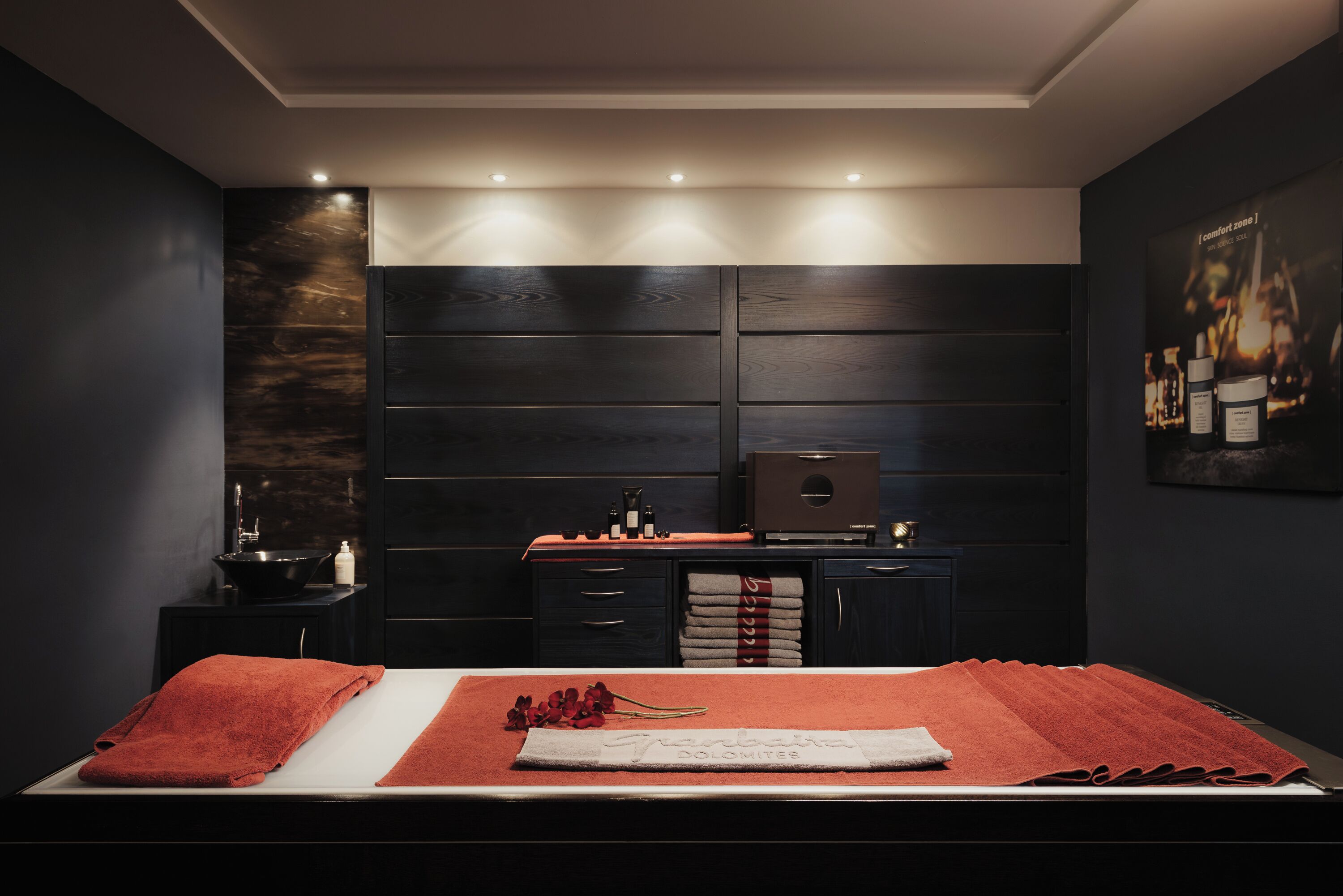 A modern bedroom with a bed, a vanity with a mirror, and a nightstand.
