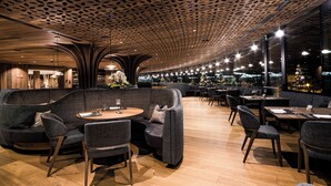 A modern restaurant interior with wooden ceiling, round tables, and comfortable seating. - Hotel Granbaita Dolomites (Selva di Val Gardena)