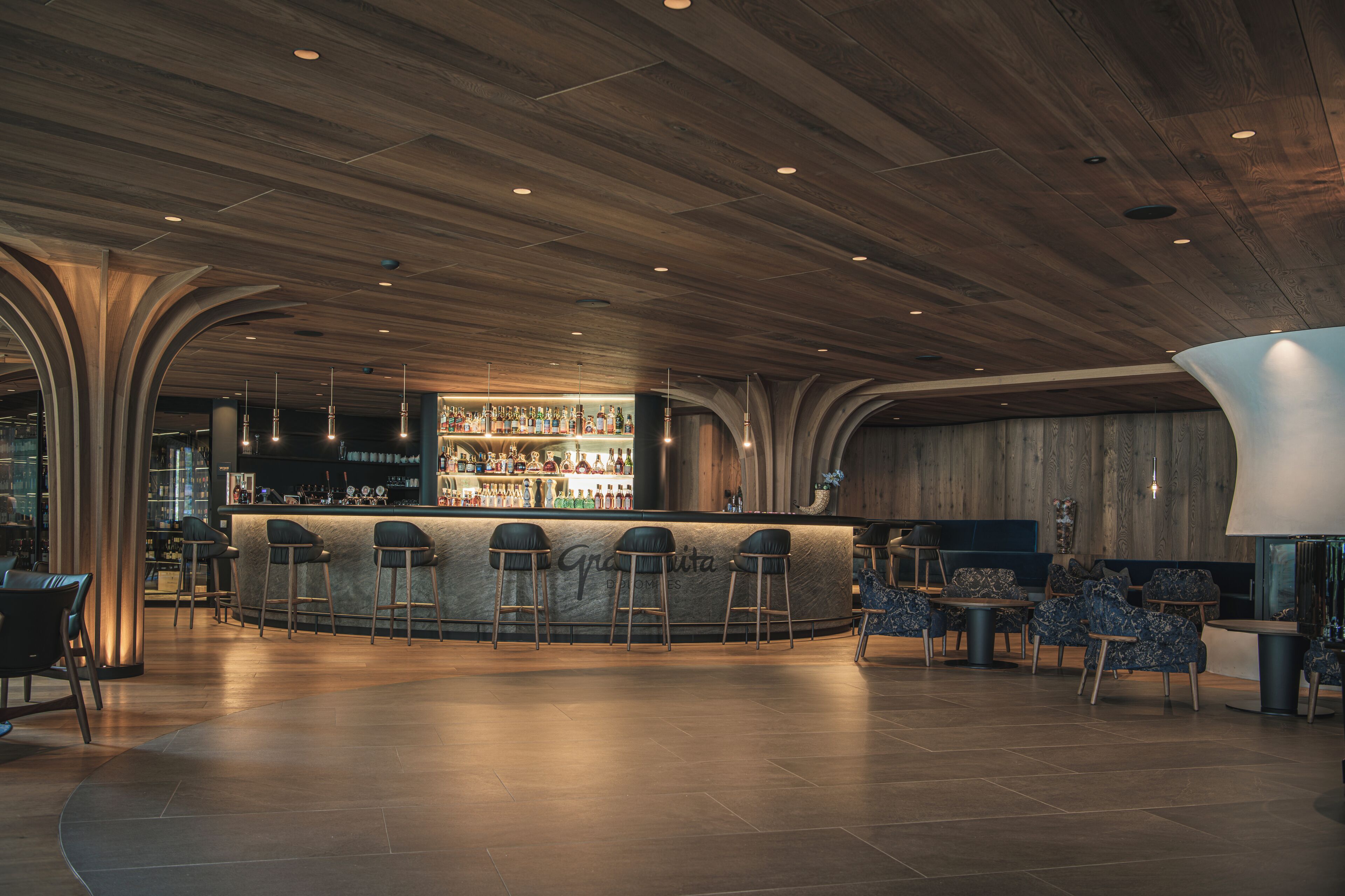 Una zona de bar con techo de madera, taburetes y barra.
