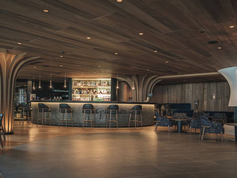 A bar area with a wooden ceiling, bar stools, and a bar counter.