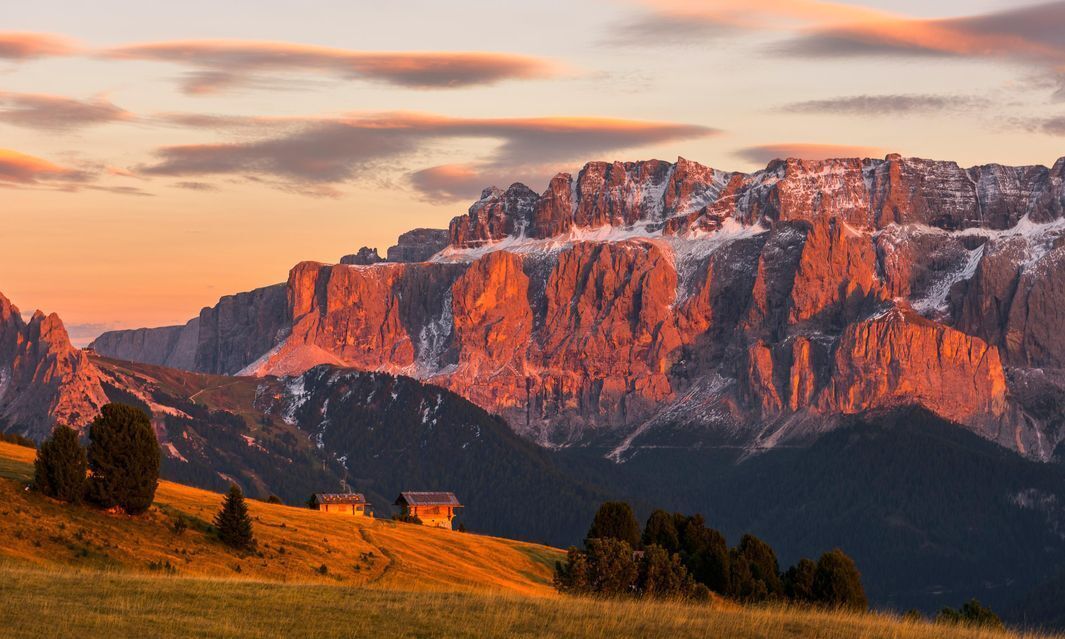 Un paisaje montañoso con una cabaña pequeña.