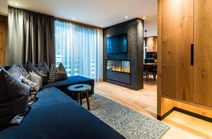 A modern living room with a dark blue sofa, a small round table, and a fireplace.