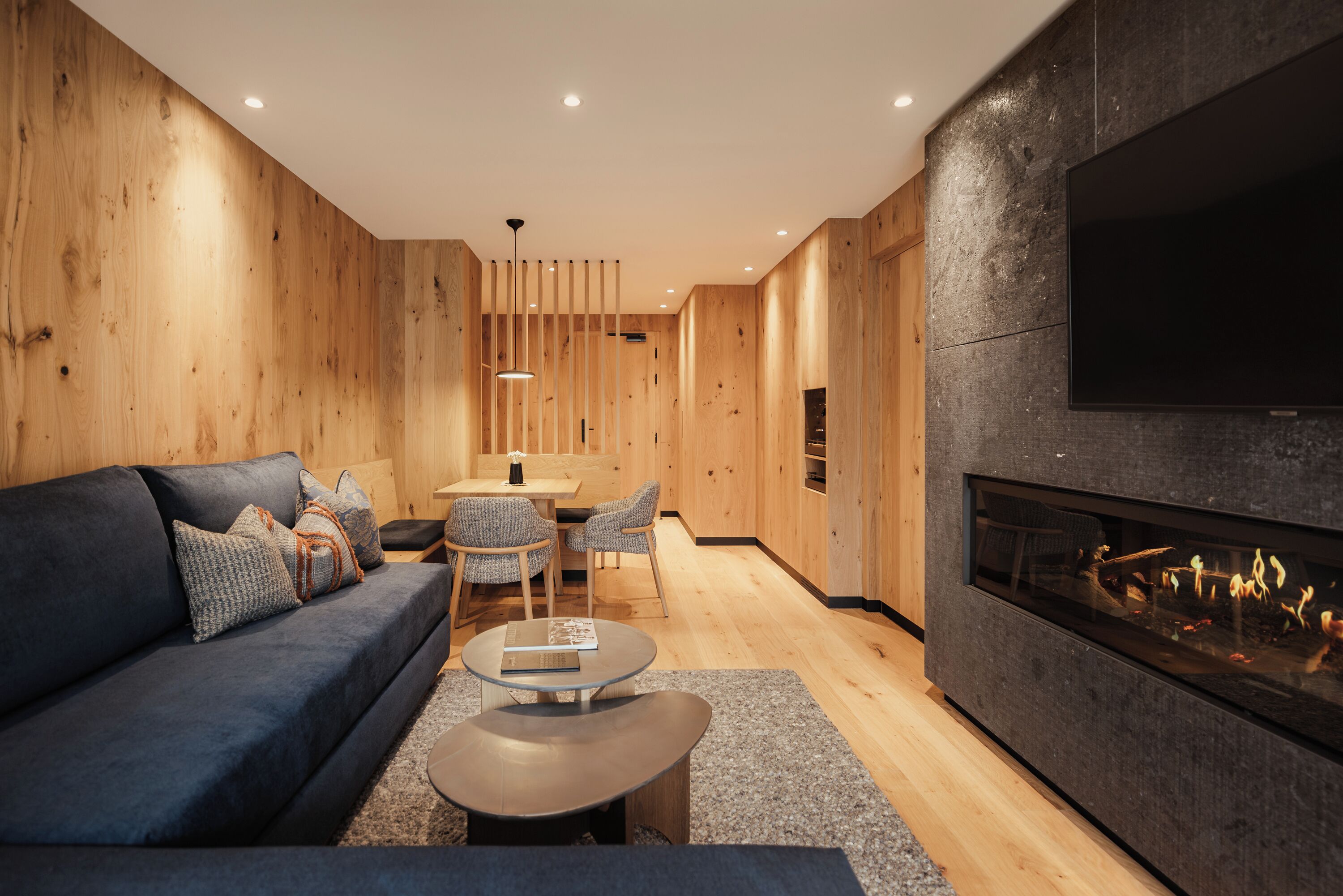 A modern living room with a dark blue sofa, a glass coffee table, and a fireplace.