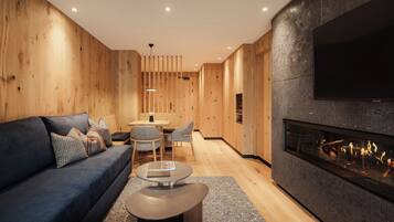 A modern living room with a dark blue sofa, a glass coffee table, and a fireplace.