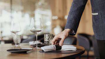 Una persona colocando una servilleta sobre una mesa redonda con una copa de vino y un cuenco decorativo.