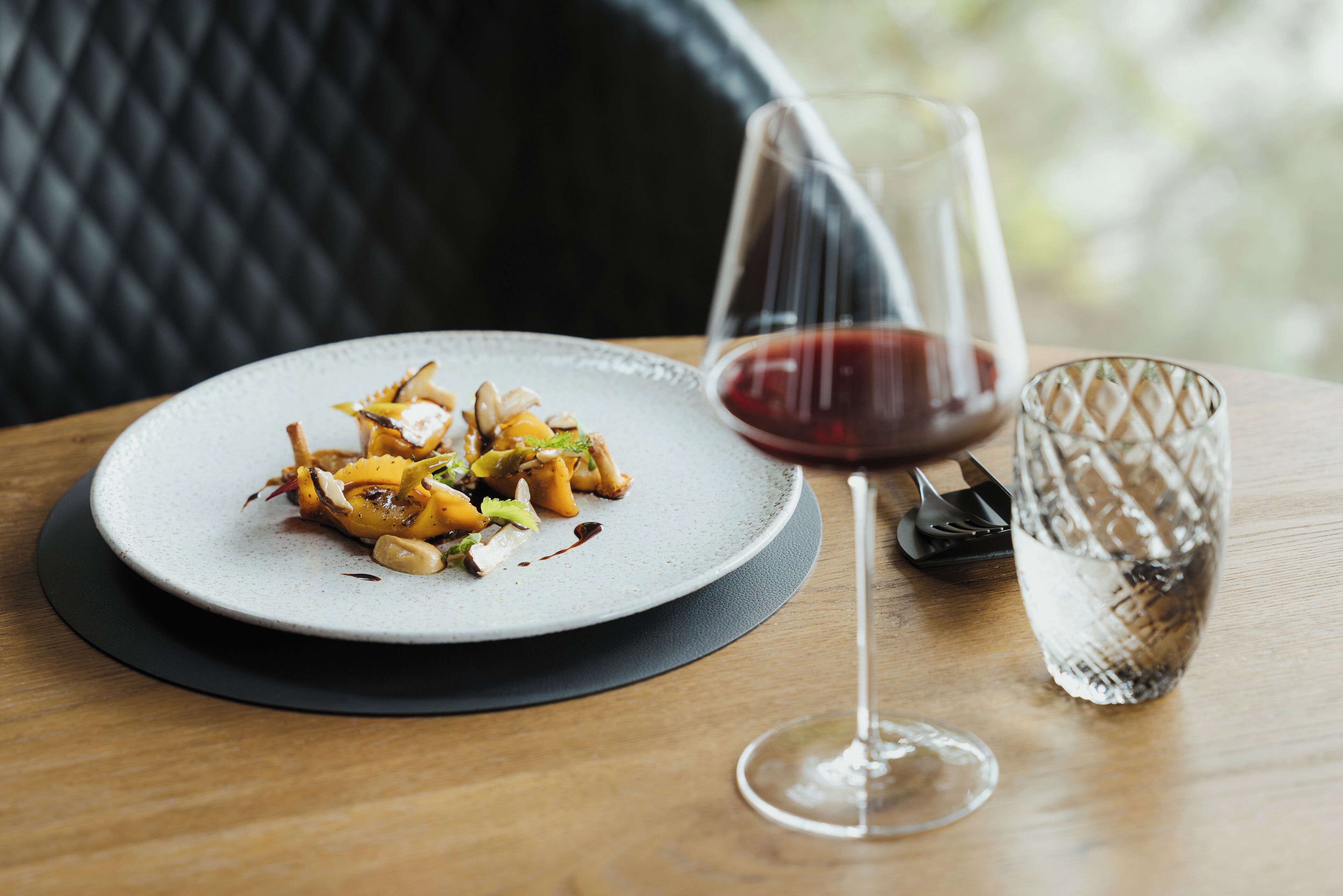 Una mesa de comedor con un plato de comida, una copa de vino y un vaso de agua.