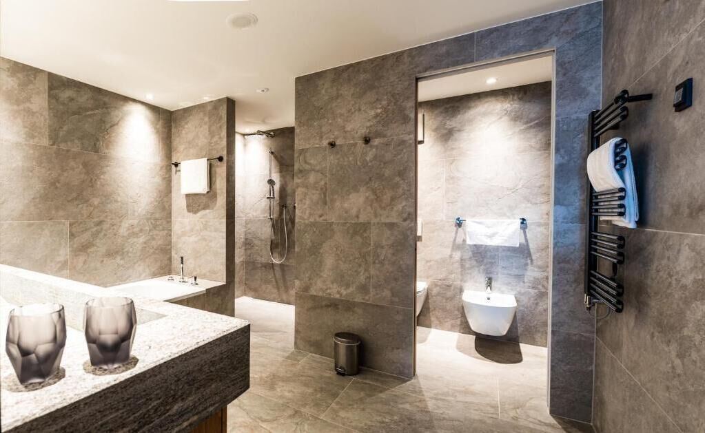 Et moderne badeværelse med en stor bruseniche, en bidet og et spejlskab med to glasvaser.