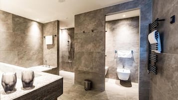 Et moderne badeværelse med en stor bruseniche, en bidet og et spejlskab med to glasvaser.