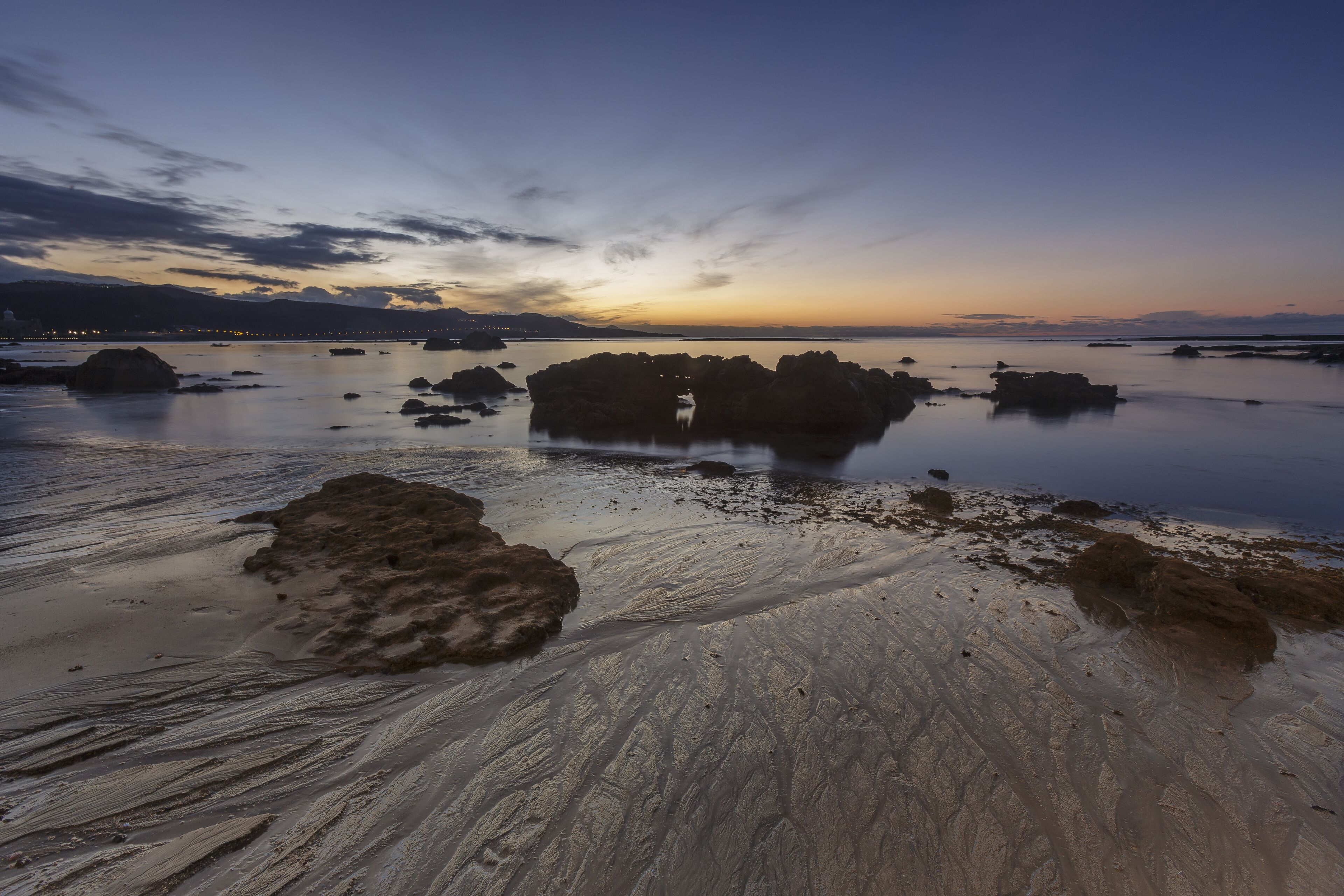 A beach with large rocks and calm water.