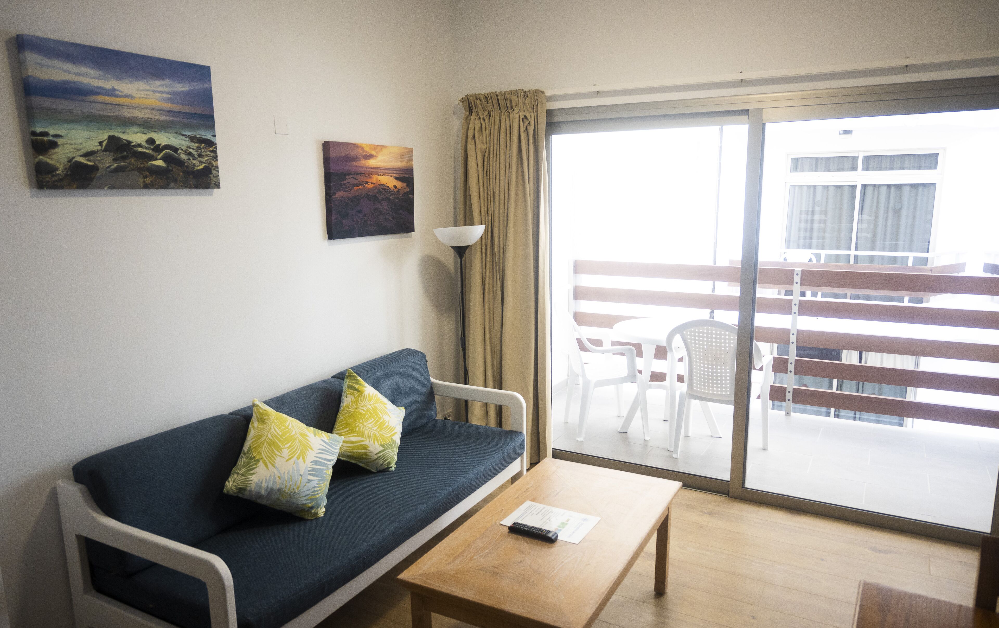 Una habitación con sofá, una mesa y vistas a un balcón con sillas.
