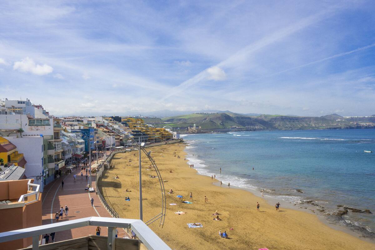 A coastal cityscape with a sandy beach, buildings, and a clear sky.