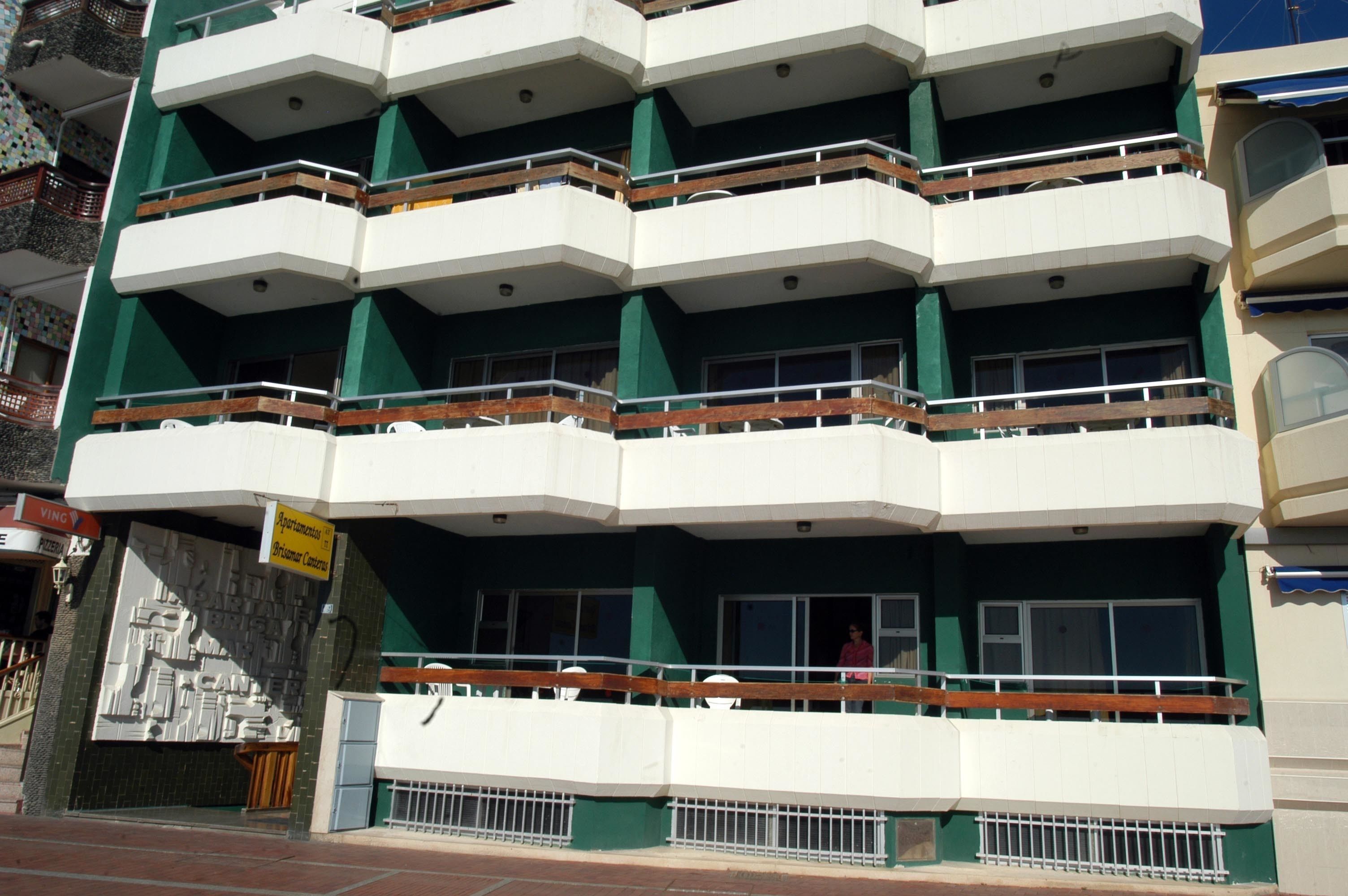 Un edificio de varios pisos con balcones, un letrero que indica un centro de negocios y una escalera que lleva a la entrada.