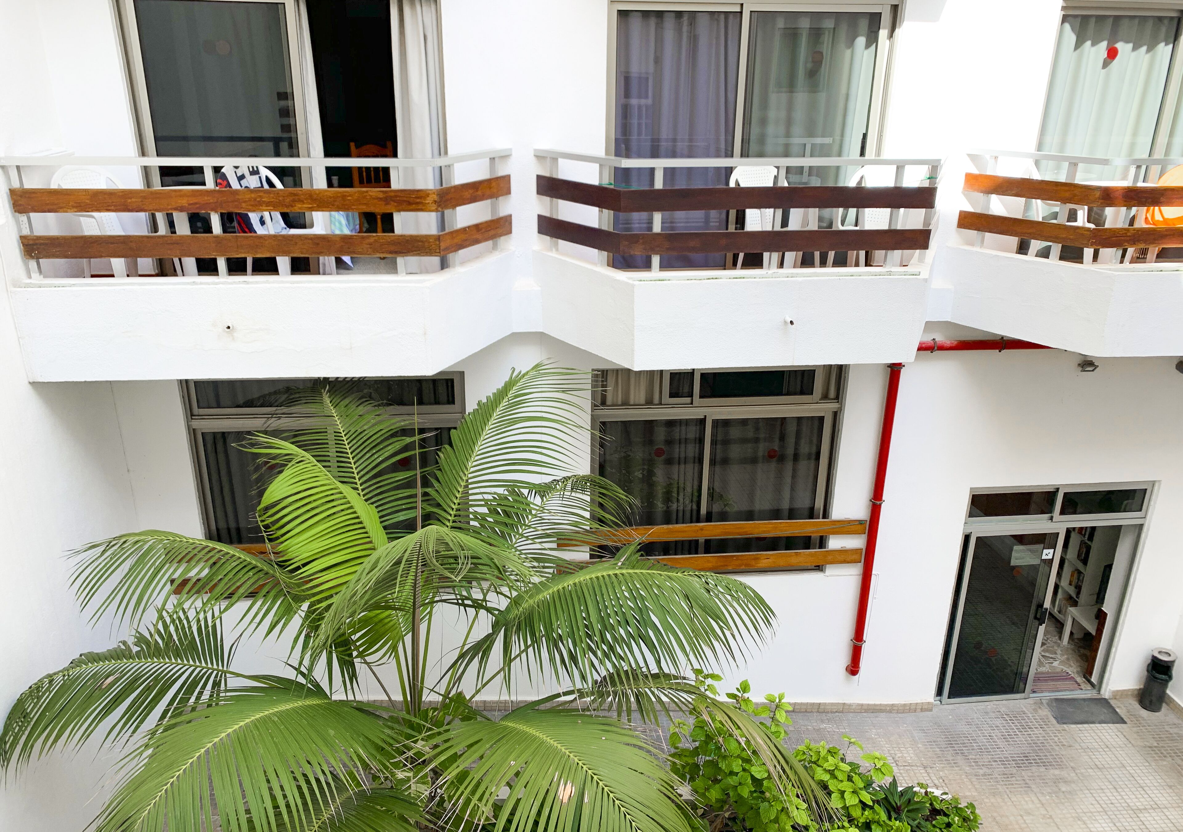 A multi-story building with balconies, large windows, and potted plants.