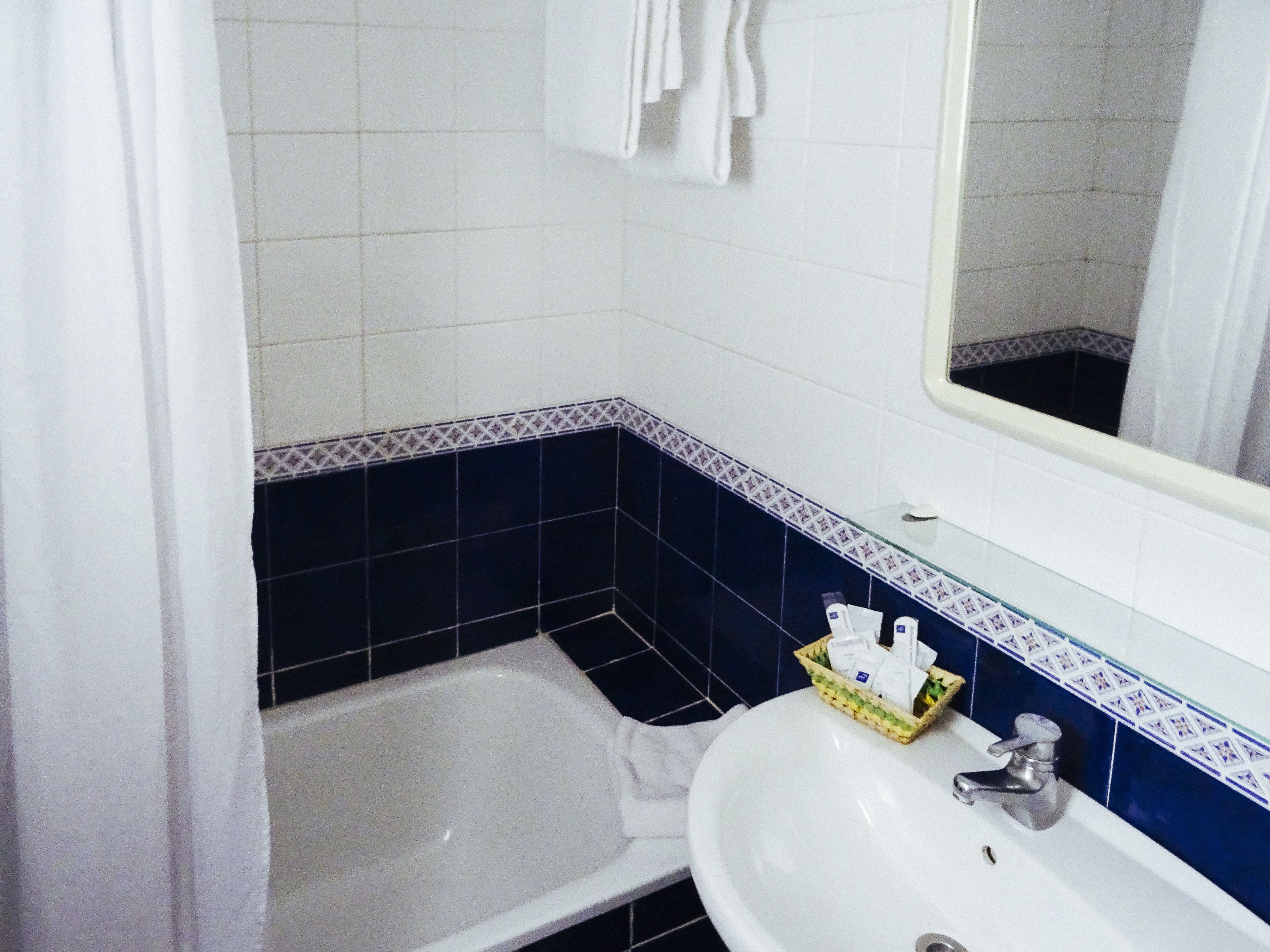 Et badeværelse med et hvitt badekar, en hvid vask og et spejl over vasken.