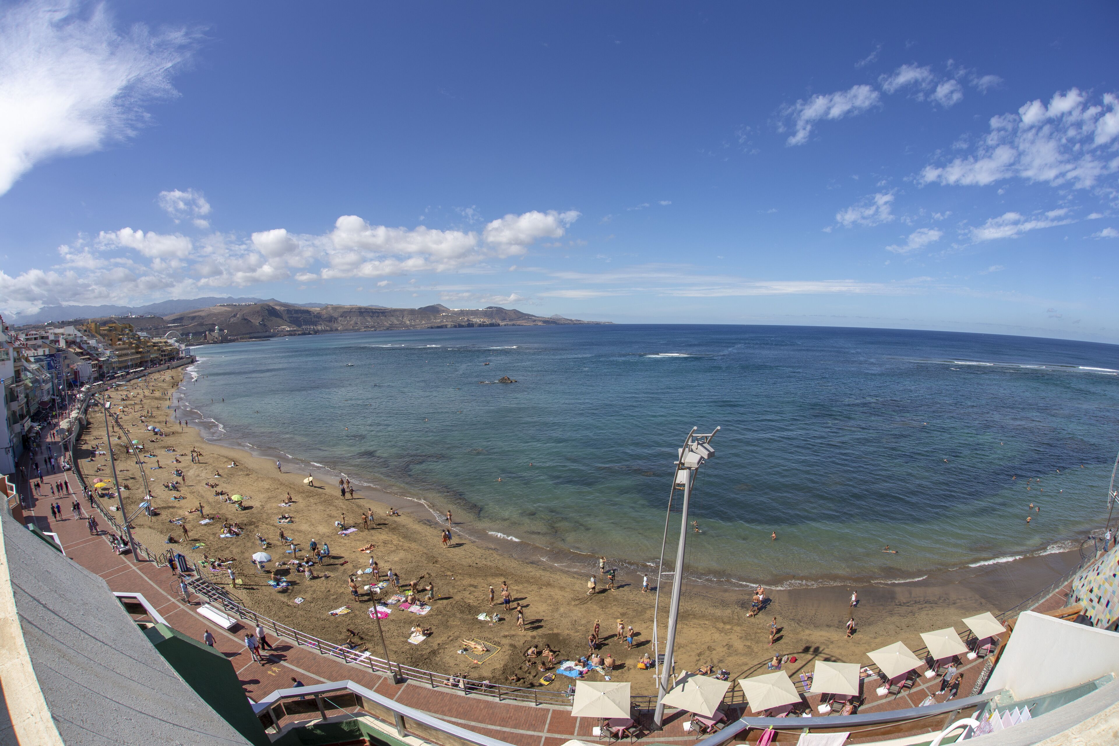 Una playa con vista despejada al océano, un paseo marítimo y un estadio.