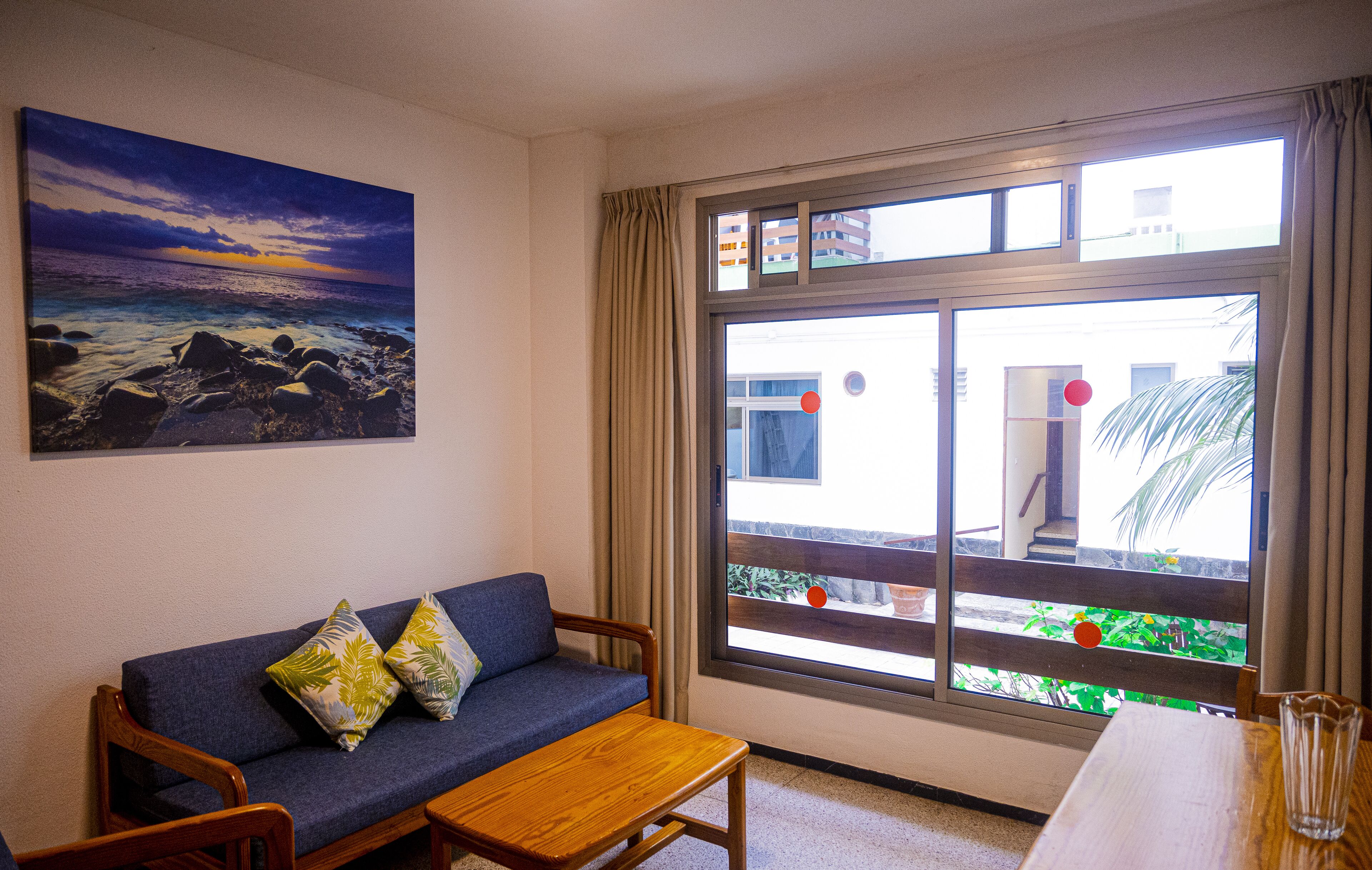 A room with a blue sofa, a wooden table, and a large window with curtains.
