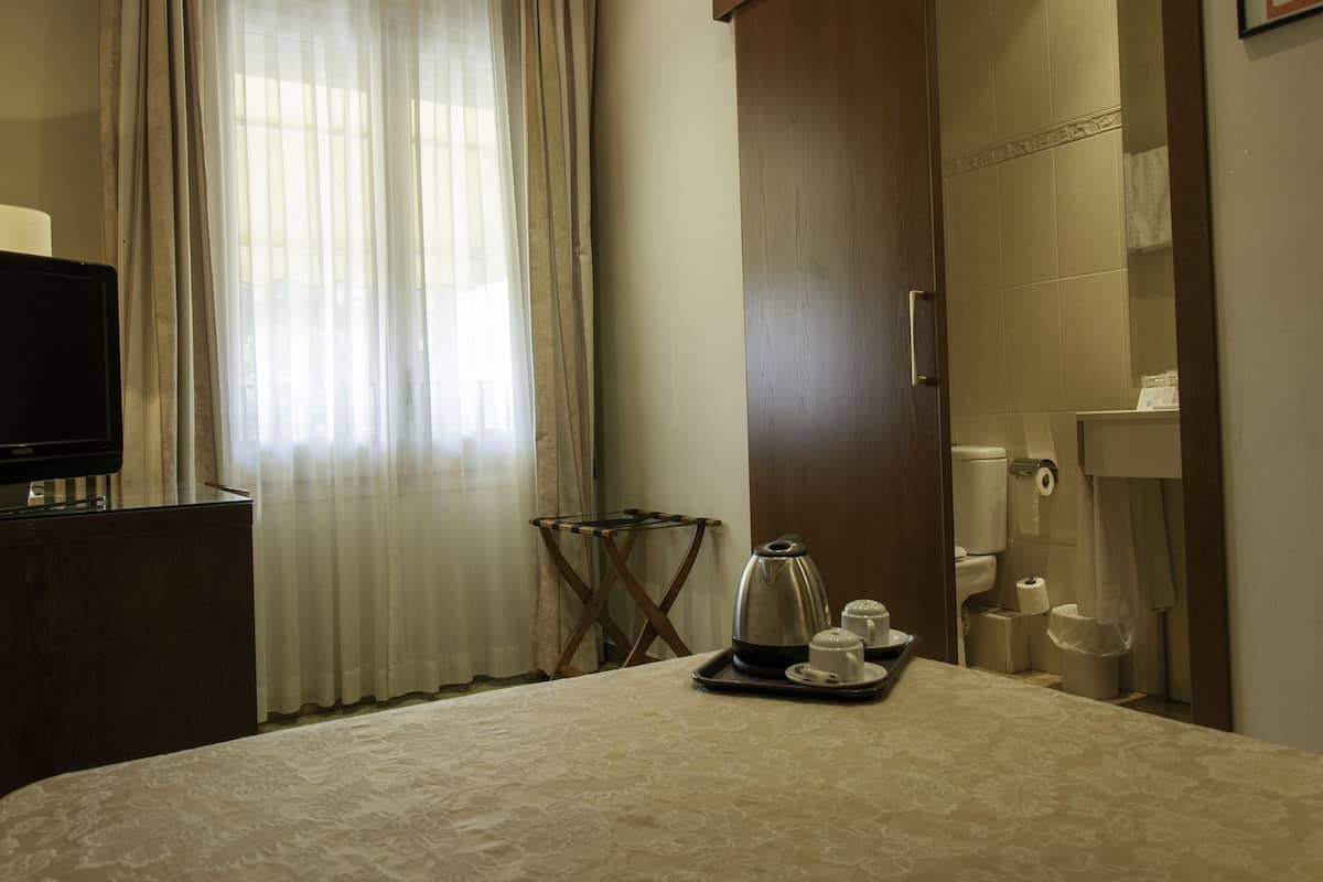A hotel room with a bed, a television, a coffee maker, and a bathroom with a toilet and sink.