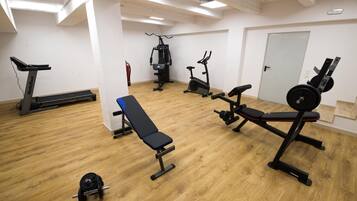 Un gimnasio con máquinas de cardio, bancos de pesas y pesas sueltas.