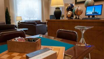 A hotel lobby with a reception desk, a coffee table, a sofa, and a dining table with chairs.