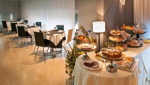 A hotel dining area with round tables, chairs, and a buffet with various food items. - Ramón Berenguer IV (Lleida)