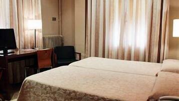 Een hotelkamer met een bed, een bureau, een stoel en een lamp.