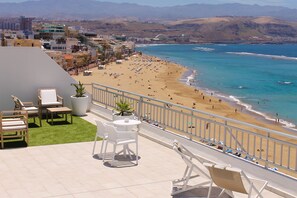 A balcony with outdoor furniture overlooking a beach and cityscape. - RK Luz Playa Suites (Las Palmas de Gran Canaria)