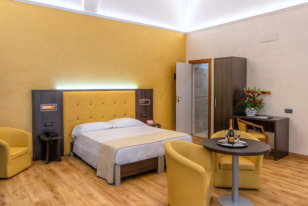 A hotel room with a bed, a desk, a chair, and a cabinet.