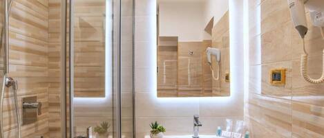 A modern bathroom with a glass shower enclosure, a sink with a mirror above it, and a hairdryer mounted on the wall.
