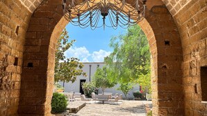 An arched brick corridor with a chandelier, outdoor seating, and greenery. - Tenuta Monacelli Lecce (Lecce)