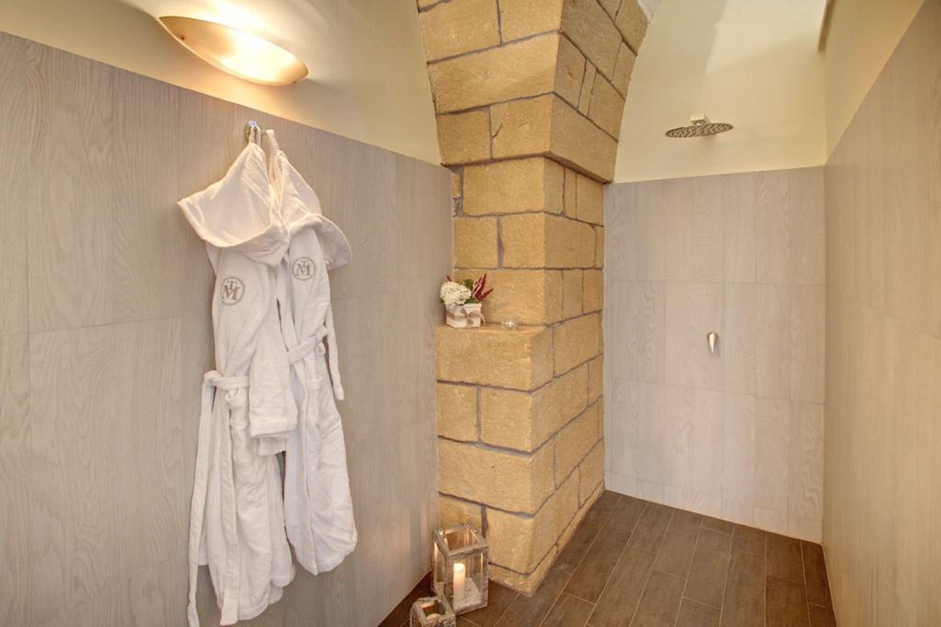 Ein Badezimmer mit Steinwand, einem aufgehängten Bademantel und einem kleinen dekorativen Gegenstand an der Wand.