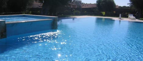 Una piscina al aire libre, sillones reclinables de piscina