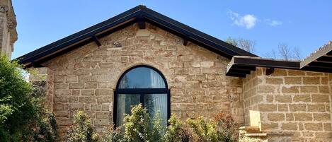 A stone building with a gabled roof and an arched window.