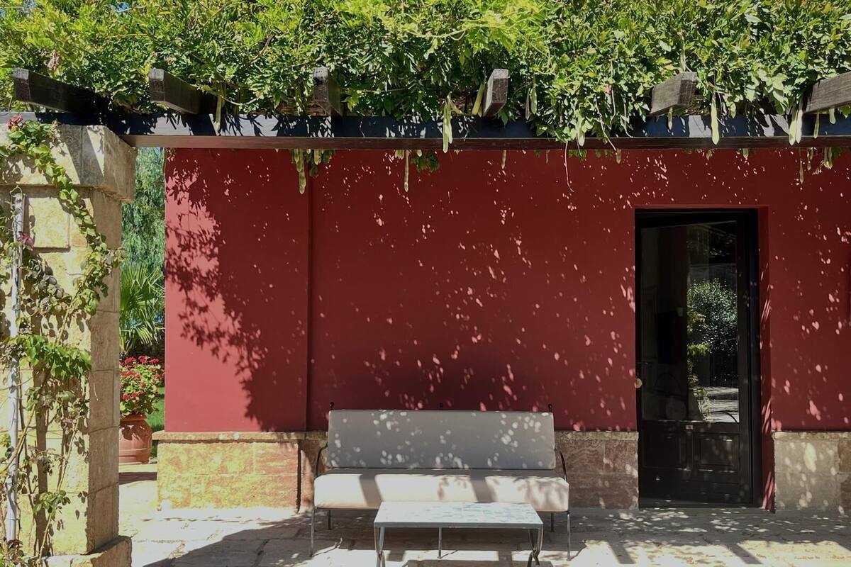 A red wall with a black door, a bench, and a table in front.
