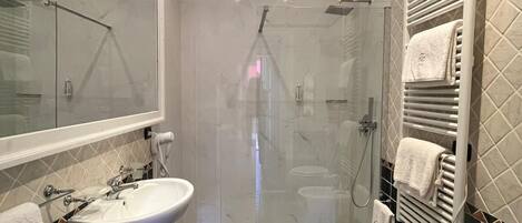 A modern bathroom with two sinks, a shower, and a toilet.