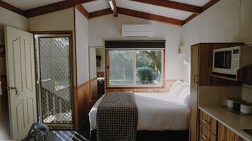 Un dormitorio con cama, ventana, puerta y kitchenette.
