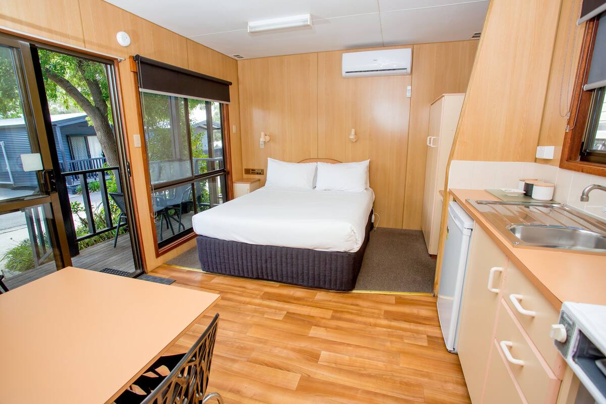 A compact room with a bed, a small kitchenette, and a dining area.