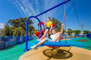 A playground with swings and a slide. - BIG4 Melbourne Holiday Park (Coburg North)
