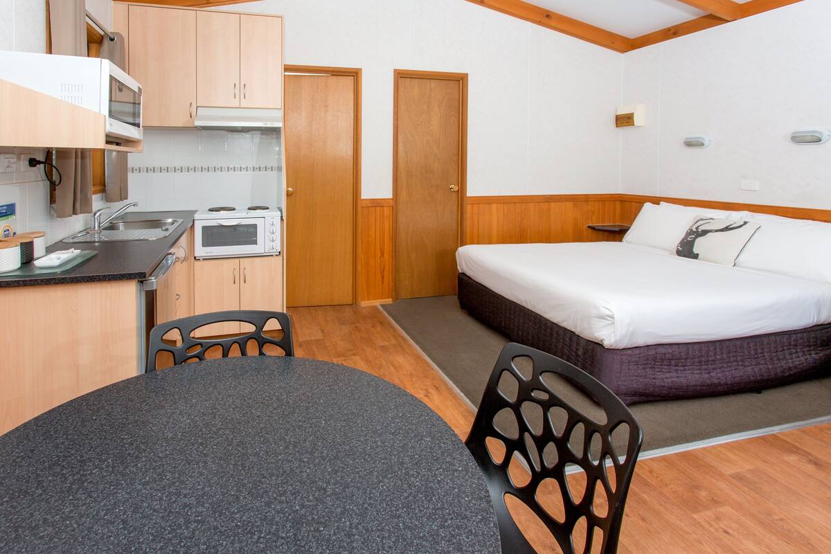A compact room with a kitchenette, a bed, and a dining area.