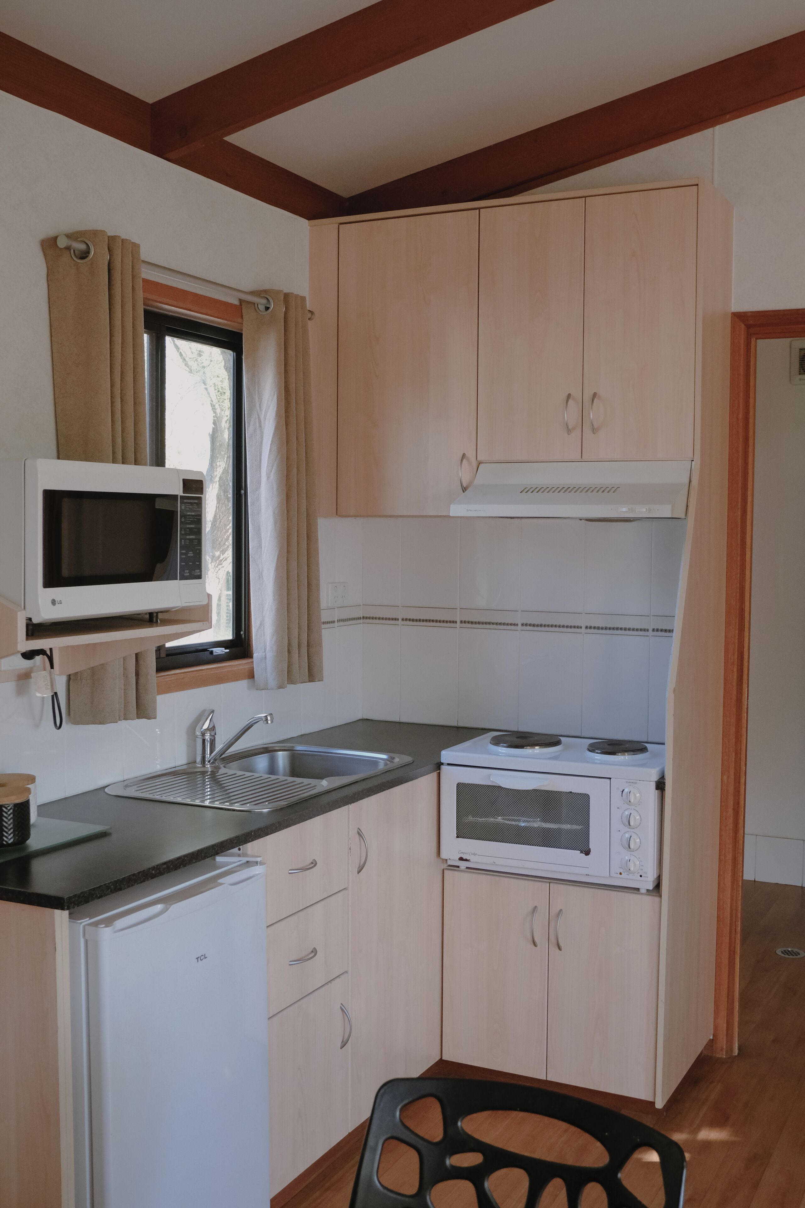 Cocina compacta con microondas, pileta, estufa y alacenas.