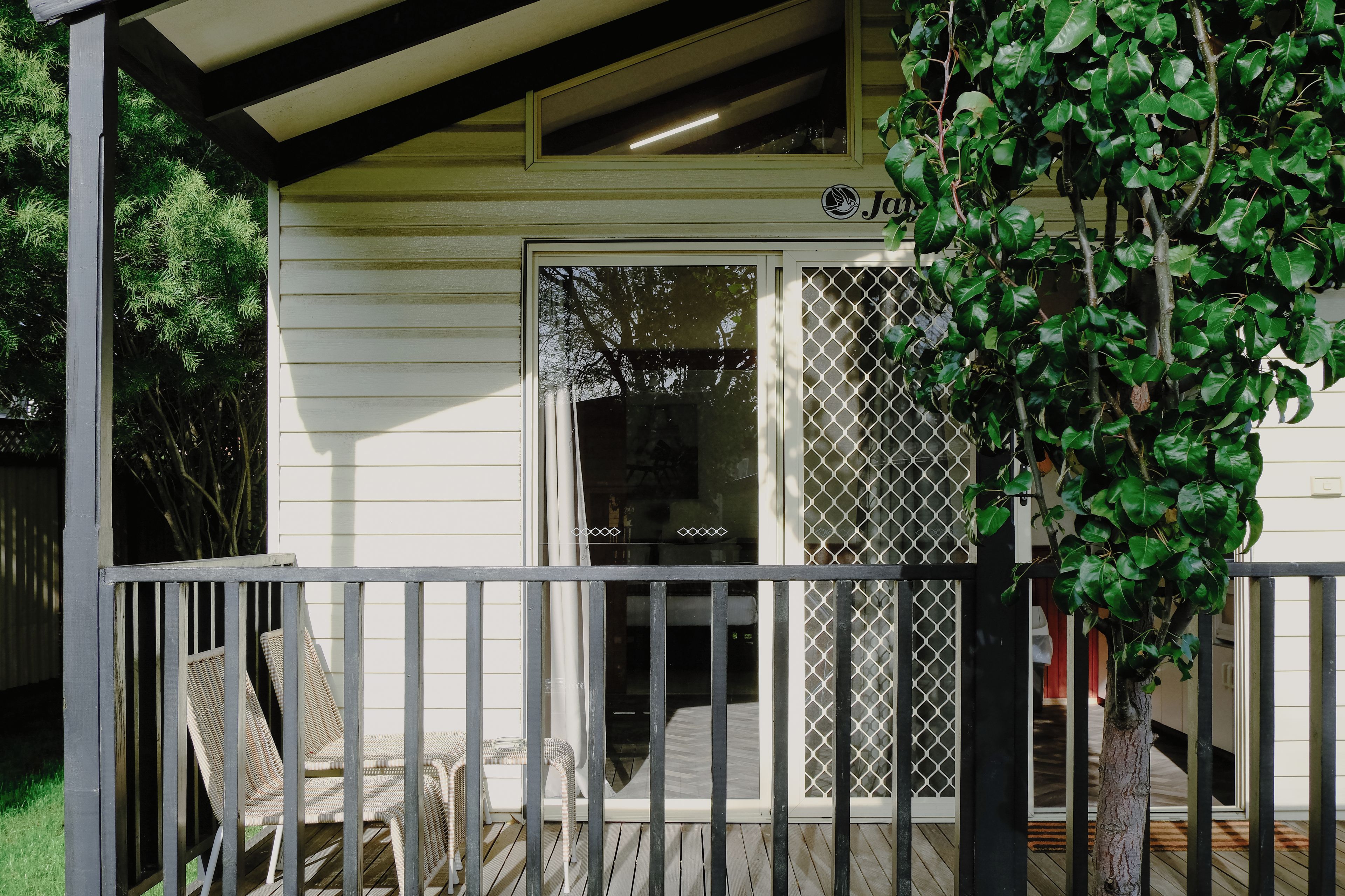 A covered porch with a white railing, a wooden table, and chairs.