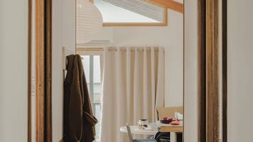 A hallway with a wooden ceiling, a dining area with a table and chairs, and a view through a window.