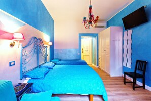 A bedroom with a blue theme, featuring a bed with a headboard, a chair, and a chandelier. - Dream Station (Rome)