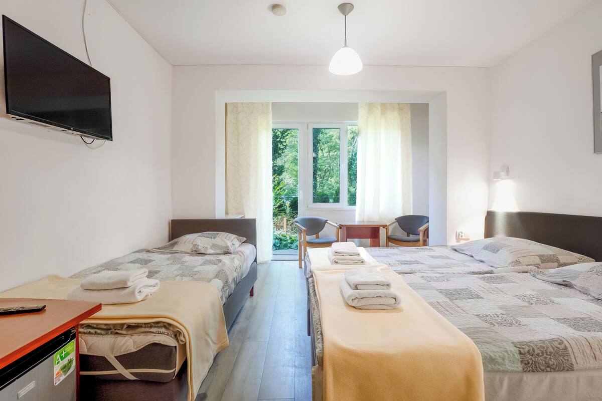 Hotellihuone, jossa on kaksi sänkyä, televisio, työpöytä ja tuoli.